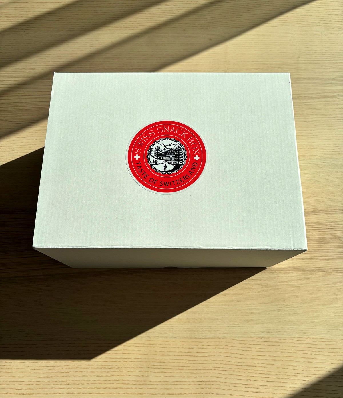 Closed Swiss Snack Box with the red seal, top view on a wooden table